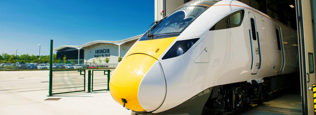 Hitachi train leaving factory building UK